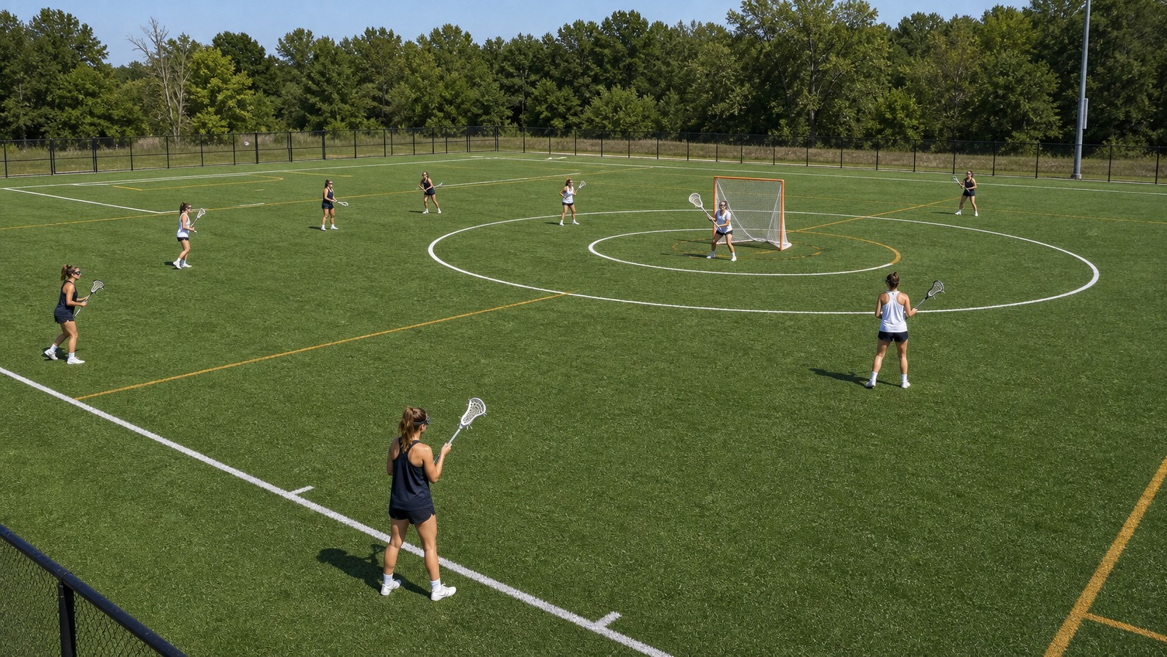 Wide unbranded women's lacrosse field with players spaced across arcs, goal circle, and field lines.